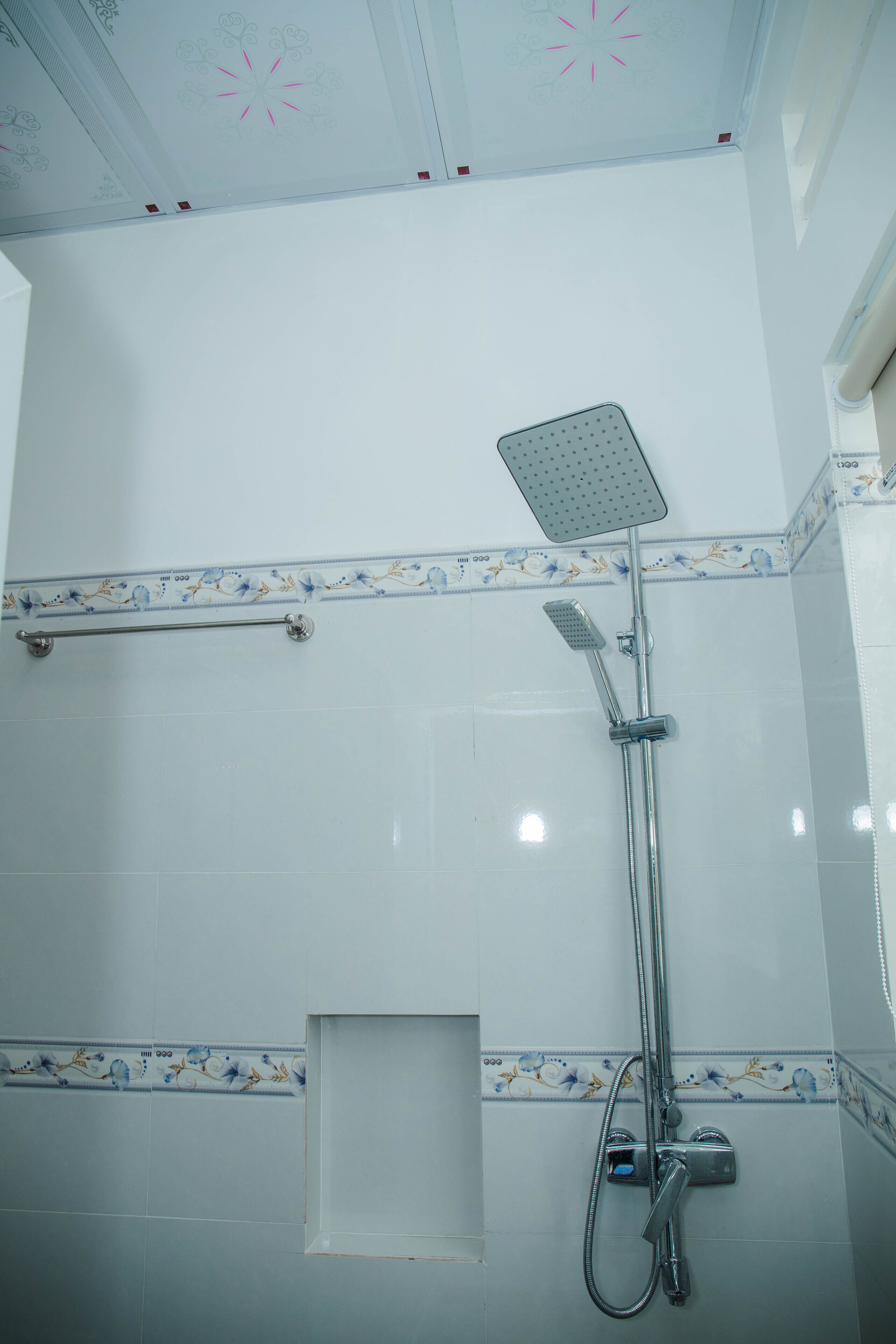 Un baño con ducha, toallero y azulejos decorativos.