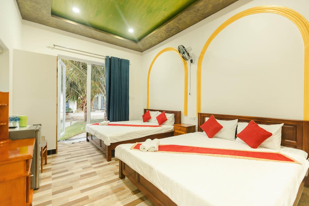 Camera d'albergo con due letti, una scrivania e vista sull'esterno.