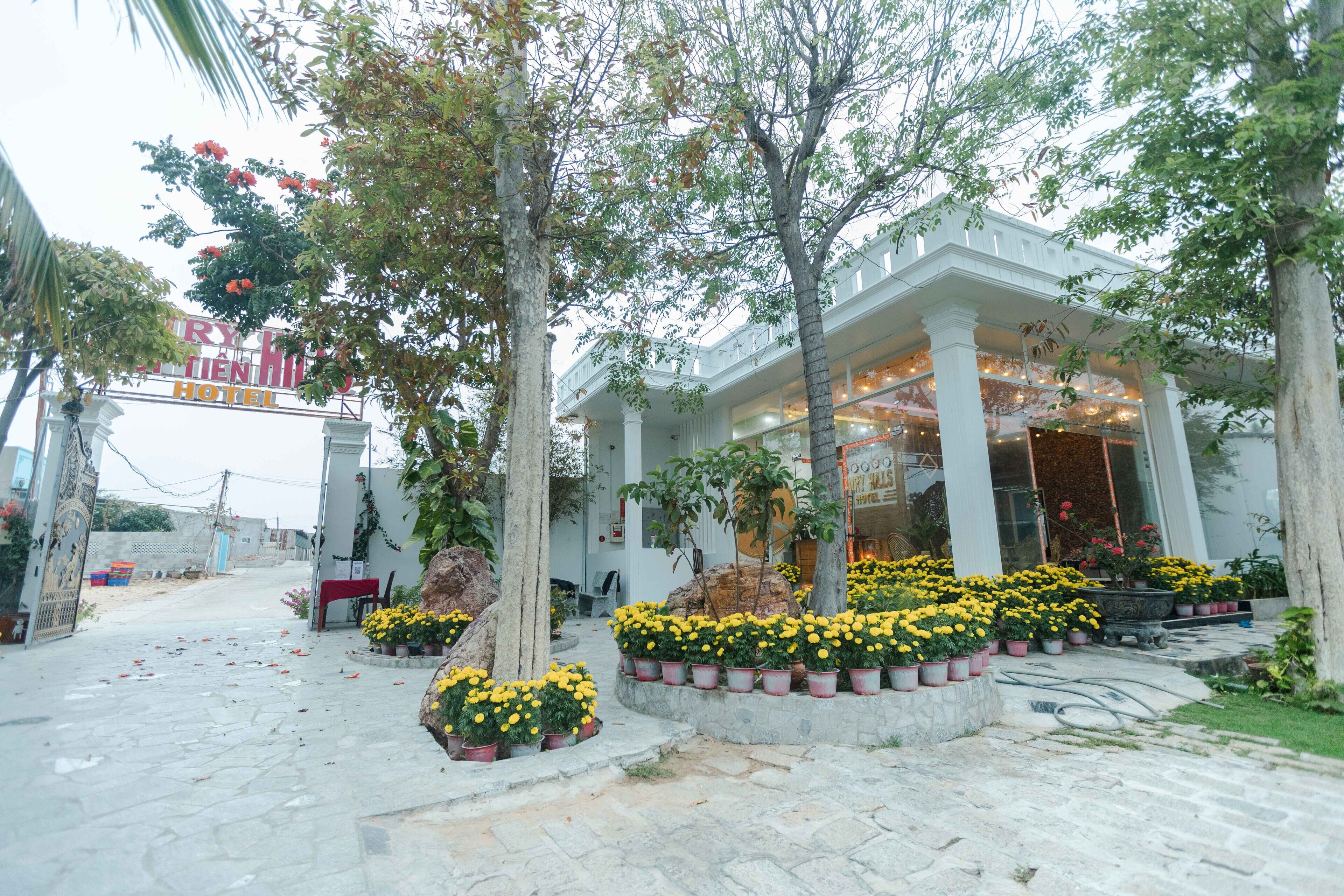 A hotel entrance with a covered walkway, potted yellow flowers, and a signboard.