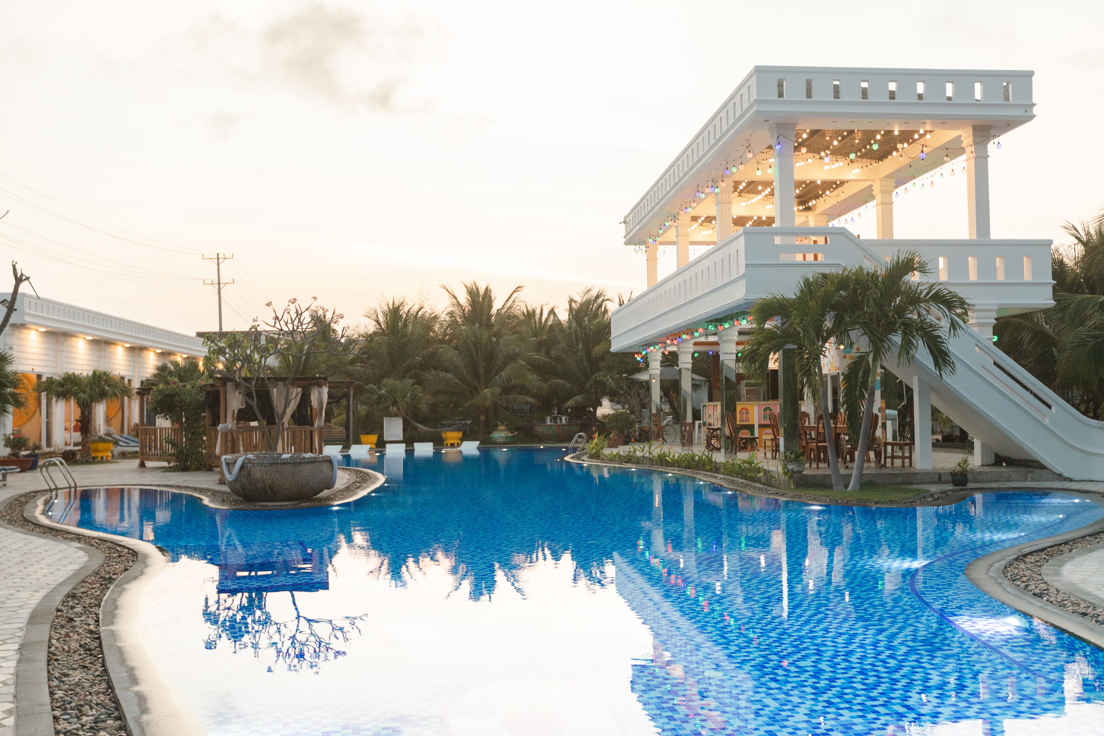 A swimming pool with a white structure and palm trees in the background.