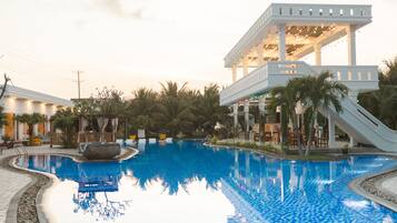 A swimming pool with a white structure and palm trees in the background.