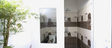 A bathroom with a shower, tiled walls, and a glass door.