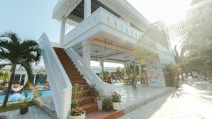 A two-story building with a staircase leading to a covered outdoor area. - Suoi TIen Hills Hotel (Mui Ne)