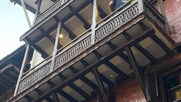 Un immeuble à plusieurs étages doté d’un balcon orné de rampes en métal finement travaillées et d’un plancher en bois.
