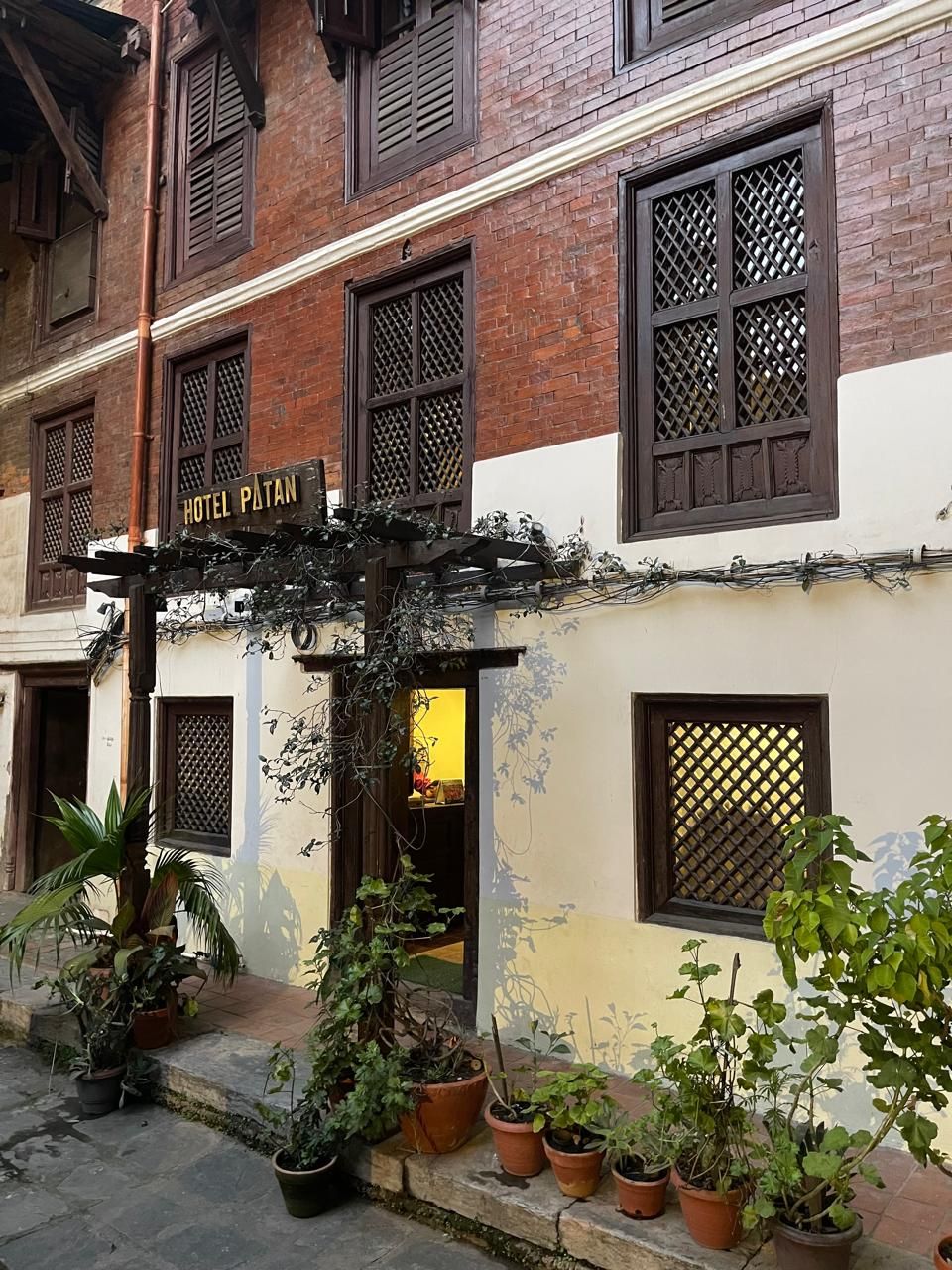 A traditional building with a sign reading "HOTEL PLOTAN" and multiple windows with lattice designs.