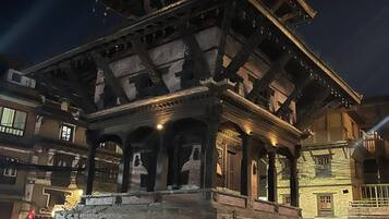 A traditional multi-tiered building with a brick base and wooden upper structure, illuminated by artificial lighting.