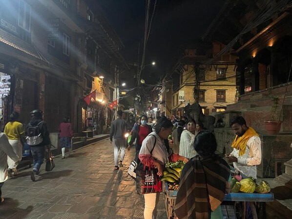 A nighttime street scene with people walking and vendors selling goods.
