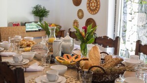 A breakfast table set with plates, cups, glasses, and a variety of food items including bread and fruit.