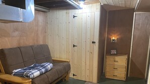 A cozy room with a brown sofa, a wooden cabinet, and a door with an emergency exit sign. - Cozy Cabin In Twin Falls (Twin Falls)