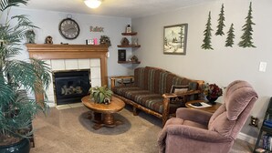 A cozy living room with a fireplace, a sofa, a chair, and a coffee table. - Cozy Cabin In Twin Falls (Twin Falls)