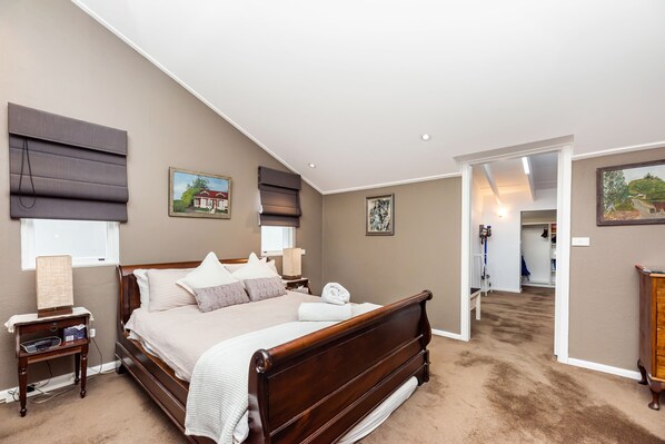 Een slaapkamer met een groot bed, nachtkastjes en een kledingkast.