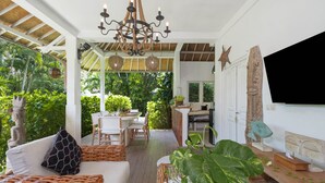 En rummelig suite med spiseplads, køkken og opholdsstue. Der er en stor plante i opholdsstuen og et tv ophængt på væggen.