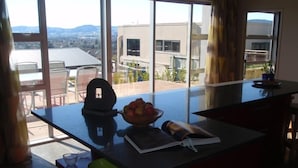 A kitchen with a large window, a bowl of fruit, and a magazine on the counter. - Luxury Rotorua Executive Home with Lake Views: Relax, Unwind, and Enjoy (Rotorua Township)