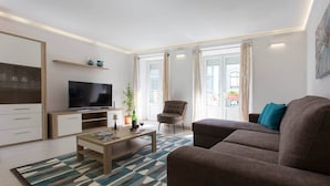 A modern living room with a sofa, a TV, a coffee table, and a chair. - Cosy duplex in Alfama (Lisboa)