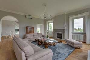 A living room with a fireplace, a chandelier, and a large window.