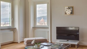 Een woonkamer met een bank, een televisie en uitzicht op een koepelgebouw.