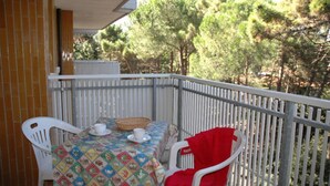 A balcony with a table set for two, chairs, and a view of trees.