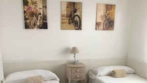 A hotel room with two single beds, a nightstand with a lamp, and three wall-mounted pictures depicting bicycles. - Vilasardemarlux 1 NEAR BARCELONA 1 (Vilassar de Mar)