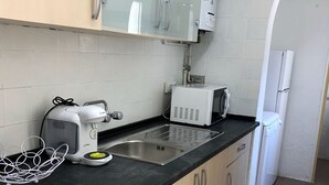 A compact kitchen with a black countertop, stainless steel sink, a coffee maker, a toaster, and a refrigerator. - Vilasardemarlux 1 NEAR BARCELONA 1 (Vilassar de Mar)