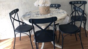 A dining area with a round table, four black chairs with 'HOME' signs, a decorative basket with flowers, and a floral painting on the wall. - Vilasardemarlux 1 NEAR BARCELONA 1 (Vilassar de Mar)