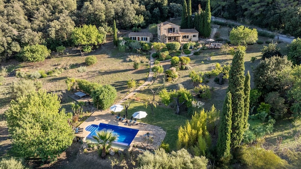 A large house surrounded by a lush garden with a swimming pool. - Luxury secluded Villa with Infinity Pool &Panoramic view 20 minutes from beaches (Campanet)