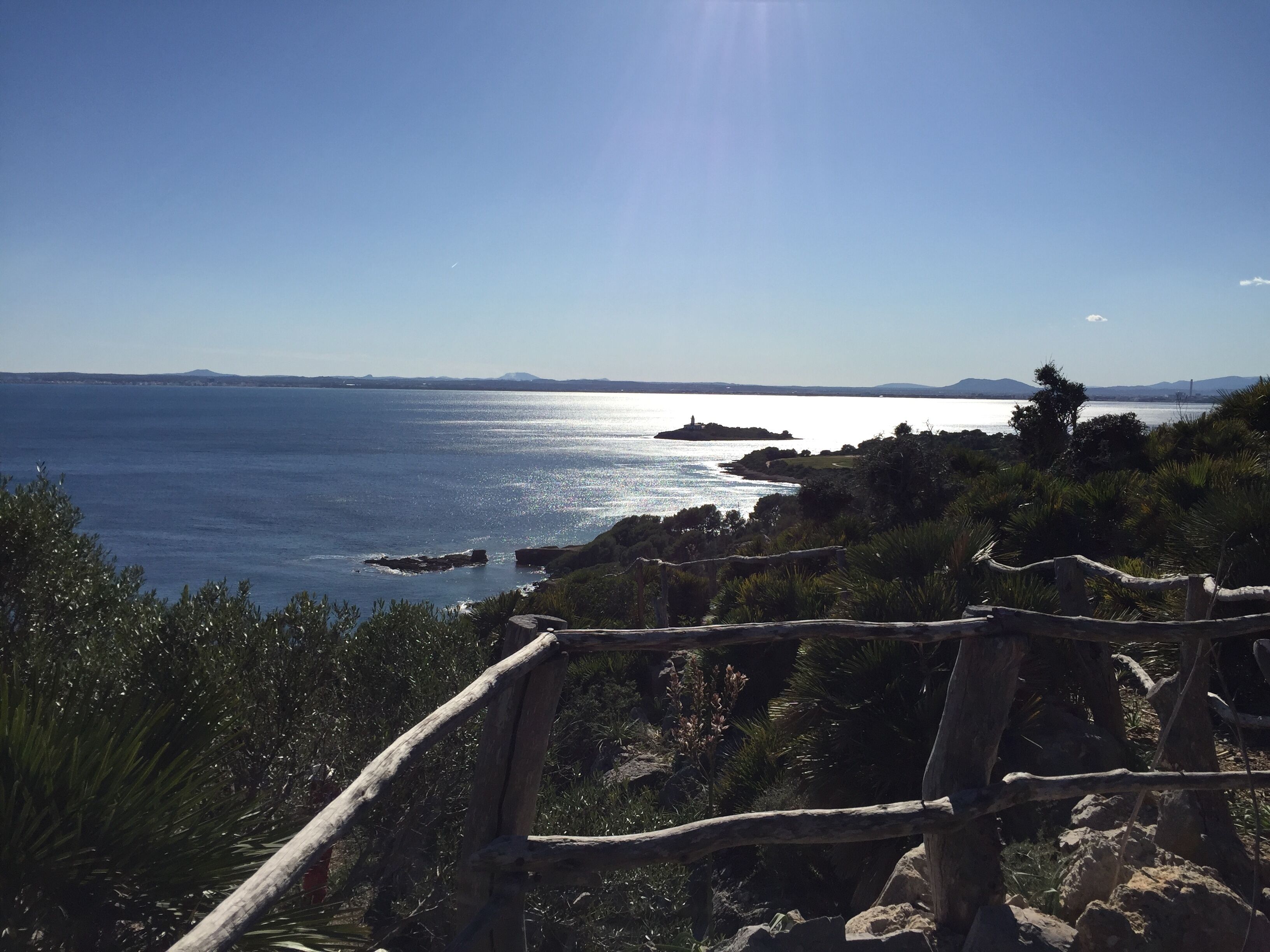 A coastal landscape with a clear sky, a body of water, and a distant landmass.