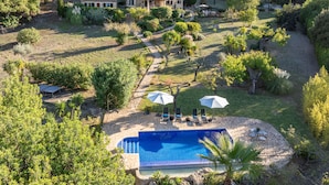 A large house surrounded by a garden with a swimming pool, outdoor seating, and a stone pathway. - Luxury secluded Villa with Infinity Pool &Panoramic view 20 minutes from beaches (Campanet)