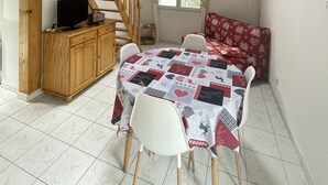 A dining area with a wooden staircase, a table with a heart-patterned tablecloth, and a sofa with a red and white cover. - Chalet - CHANTEMERLE (Saint-Chaffrey)