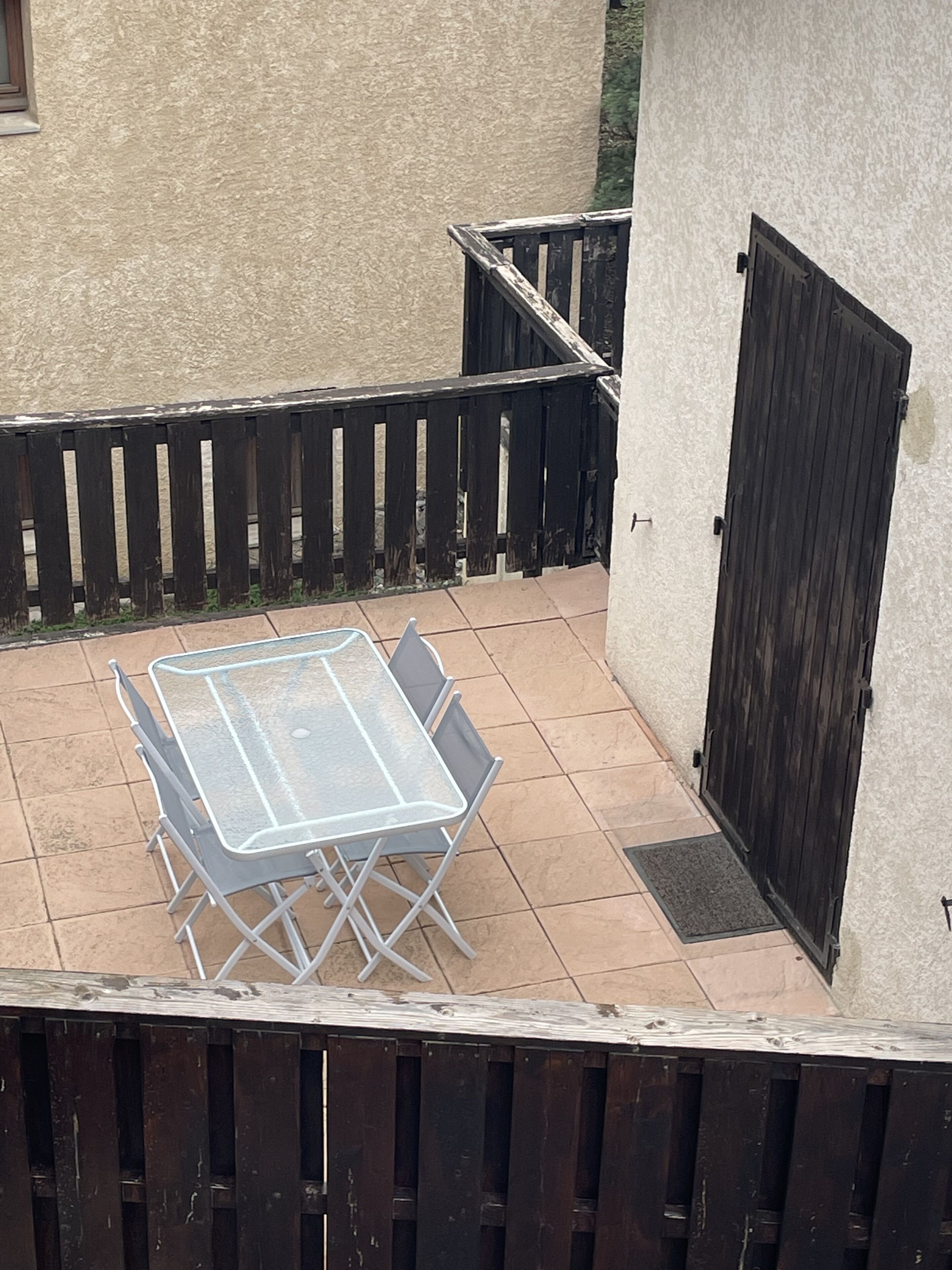 A patio with a table and chairs, a wooden fence, and a door.