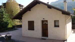 A small, single-story building with a sloped roof, a chimney, and a door with a window on the side. - Chalet - CHANTEMERLE (Saint-Chaffrey)