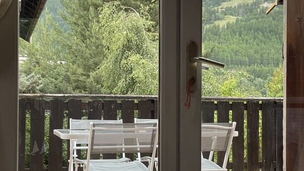 A room with a view of a wooden deck and chairs outside. - Chalet - CHANTEMERLE (Saint-Chaffrey)
