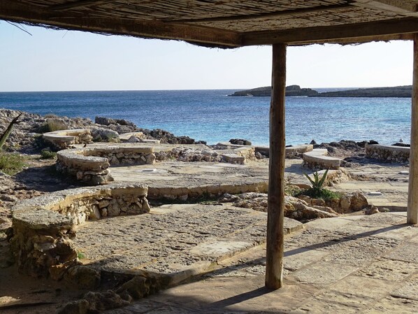 Ancient ruins with stone structures and a view of the sea.