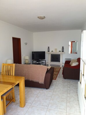 Una sala de estar con televisión, sofá y chimenea.