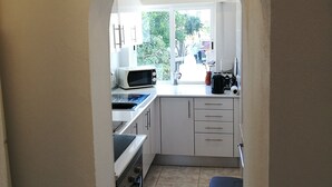 Een keuken met witte kastjes, een magnetron en een koffiezetapparaat.
