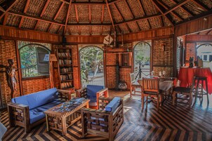 Una habitación acogedora y rústica con techo de madera, un sofá azul, una mesa de madera y una estantería.