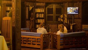 Ein gemütliches Bücherzimmer mit Holzregalen, einem Fernseher und bequemen Sitzgelegenheiten.