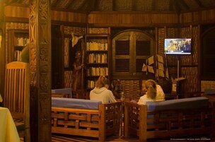 Una biblioteca acogedora con estanterías de madera, un televisor y zonas de estar cómodas.