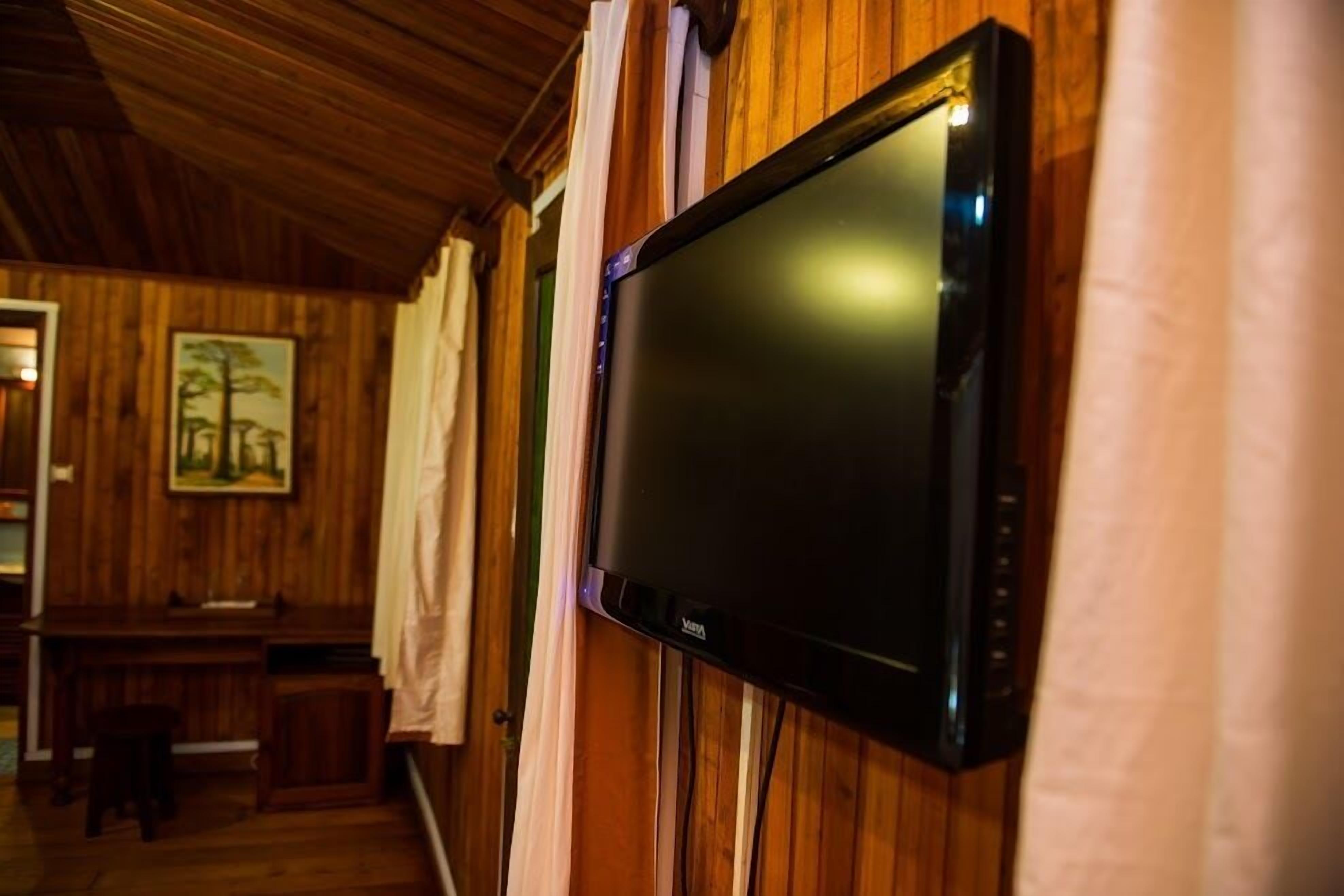 Un televisor montado en una pared de madera en una habitación con techo de madera y un banco.
