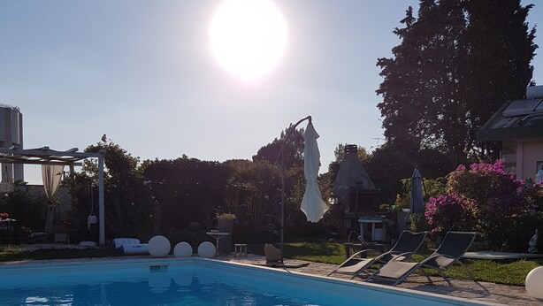 A clear blue swimming pool with lounge chairs and a pergola.