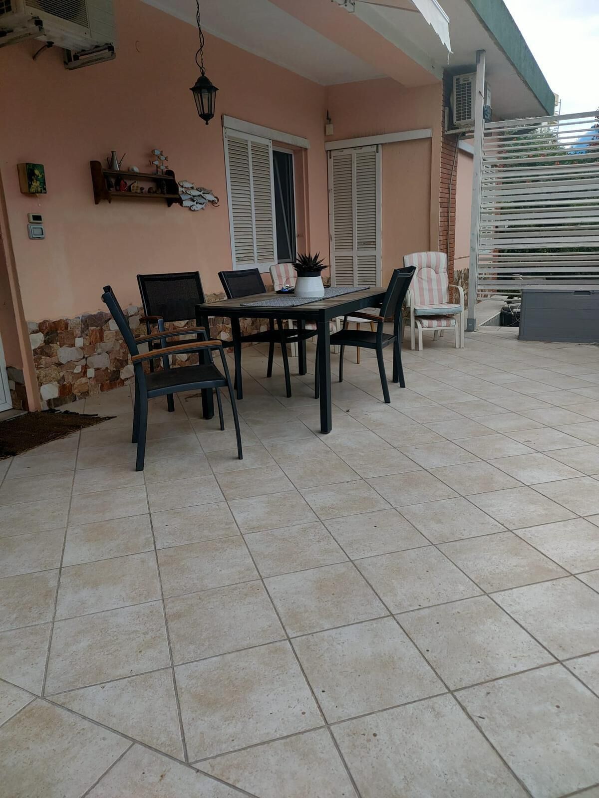A patio with a table and chairs, a potted plant, and a stone wall.