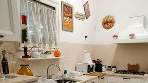A kitchen with white cabinets, a stove, a microwave, and a sink. There are decorative items on the wall and a clock.