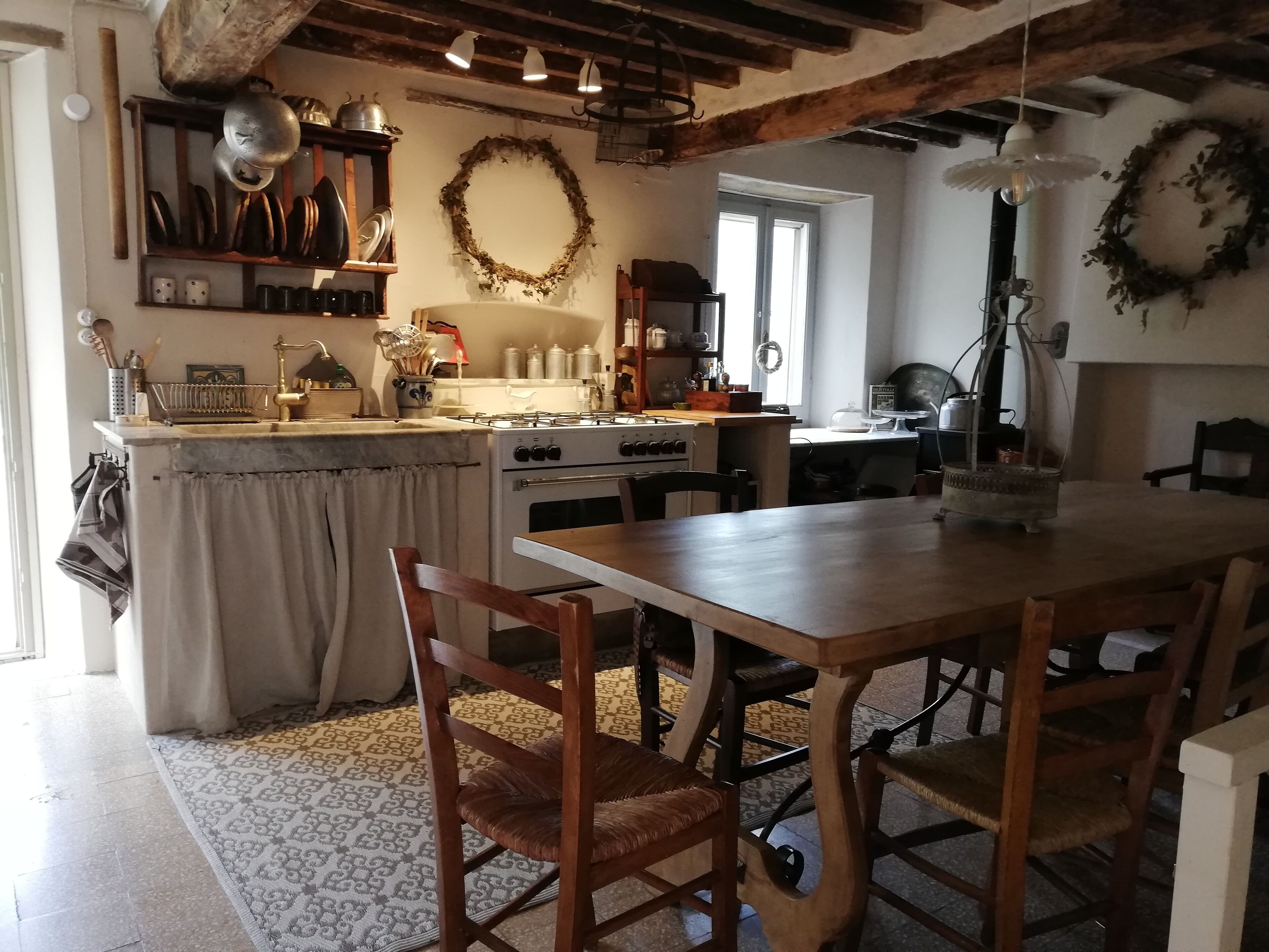 A rustic kitchen with wooden furniture, a gas stove, and a dining table with chairs.