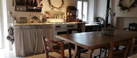 Une cuisine rustique, avec des meubles en bois, une cuisinière à gaz et une table à manger entourée de chaises.