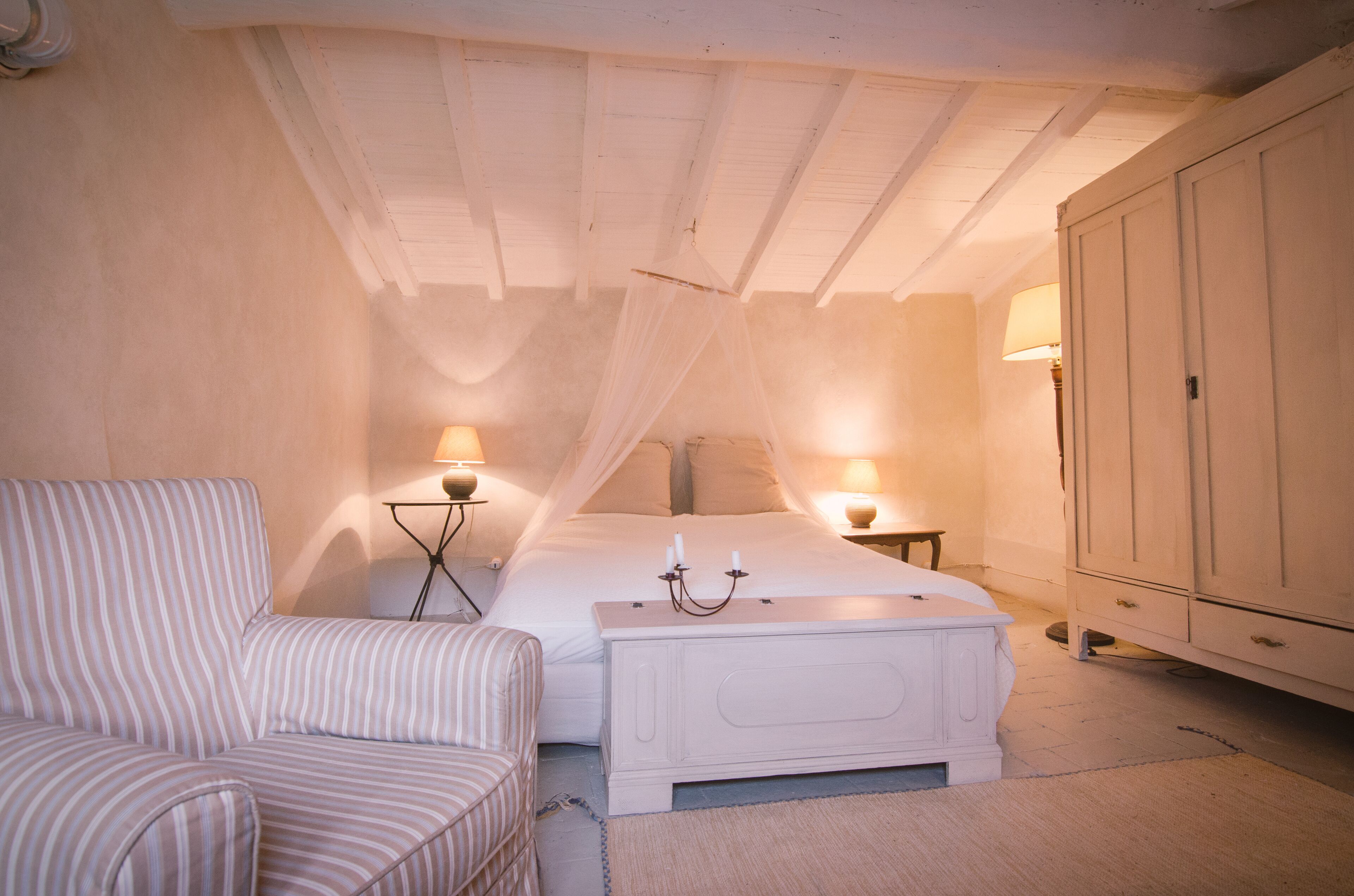 A bedroom with a bed, a bedside table, a chair, and a wardrobe.