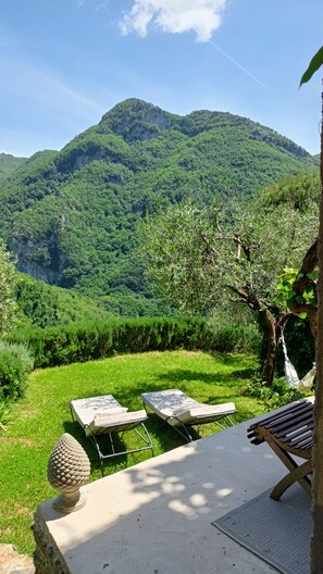 Un jardín con vista a la montaña, mobiliario exterior y una hamaca.