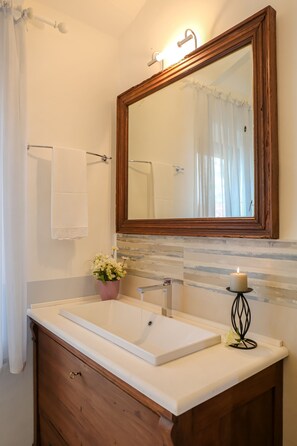 Une salle de bain avec un meuble-lavabo en bois, un grand miroir et un lavabo blanc.