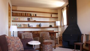 Una sala de estar acogedora con chimenea, un sofá, sillones, una mesa de centro y estanterías.