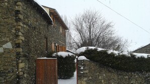 Un edificio de piedra con cerca de madera y suelo cubierto de nieve.