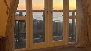 Una habitación con un amplio ventanal corredero que da a un balcón con vistas al mar.