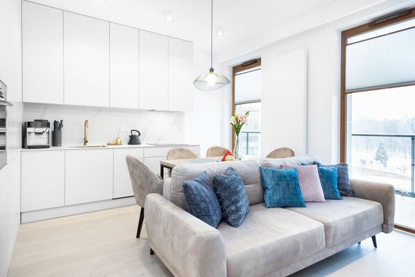 Una sala de estar moderna con un sofá, una mesa de comedor y una zona de cocina.
